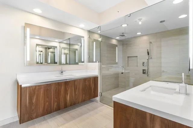 a bathroom with a double vanity sink a large mirror and shower