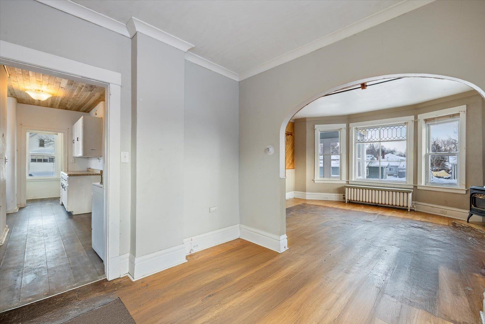 217 3rd Avenue Northwest Chisholm, MN 55719 - Photo 13 of 47 Unfurnished room with hardwood / wood-style flooring, plenty of natural light, radiator heating unit, ornamental molding, and a wood stove