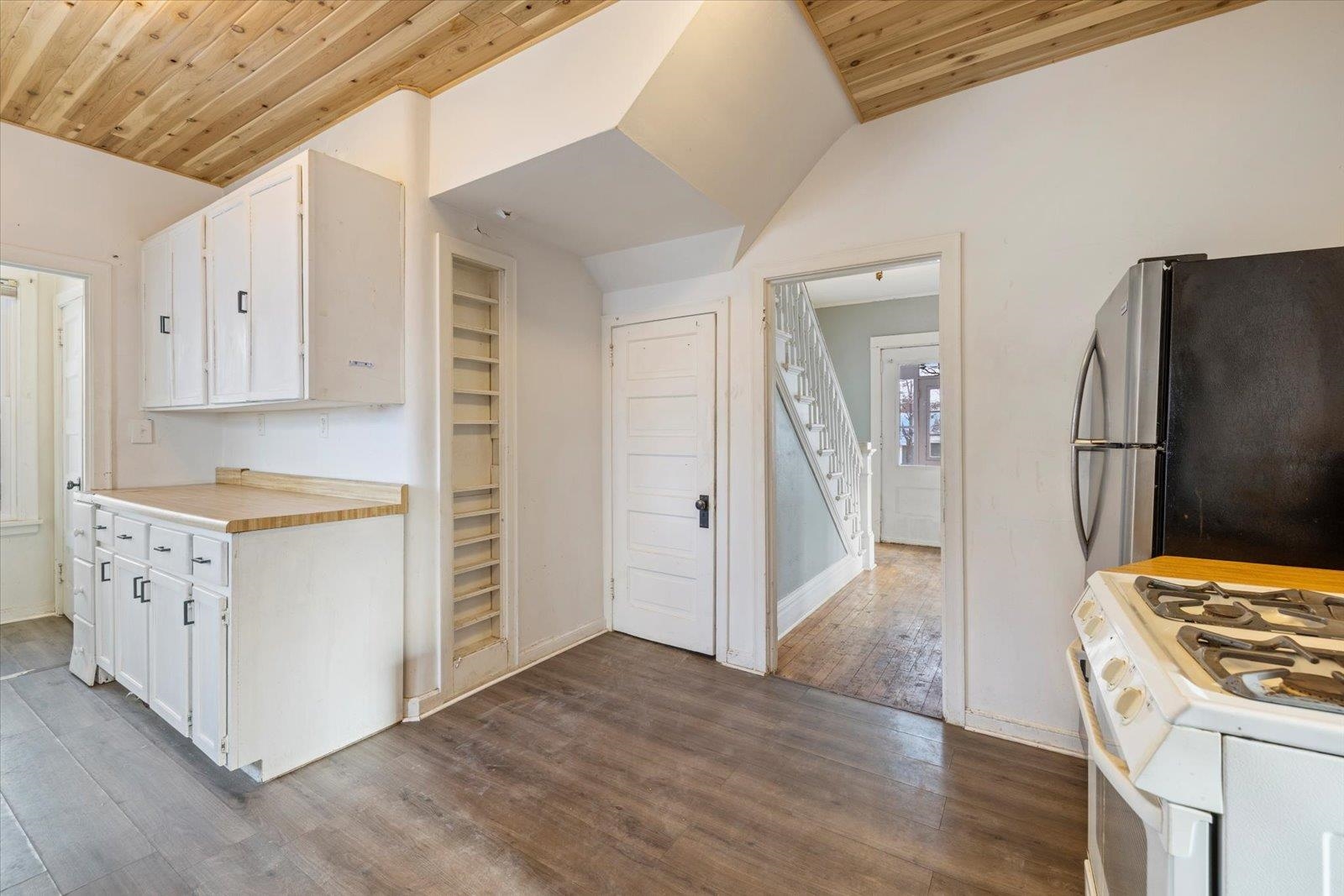 217 3rd Avenue Northwest Chisholm, MN 55719 - Photo 14 of 47 Kitchen with light countertops, white cabinetry, wood ceiling, freestanding refrigerator, and dark wood-type flooring
