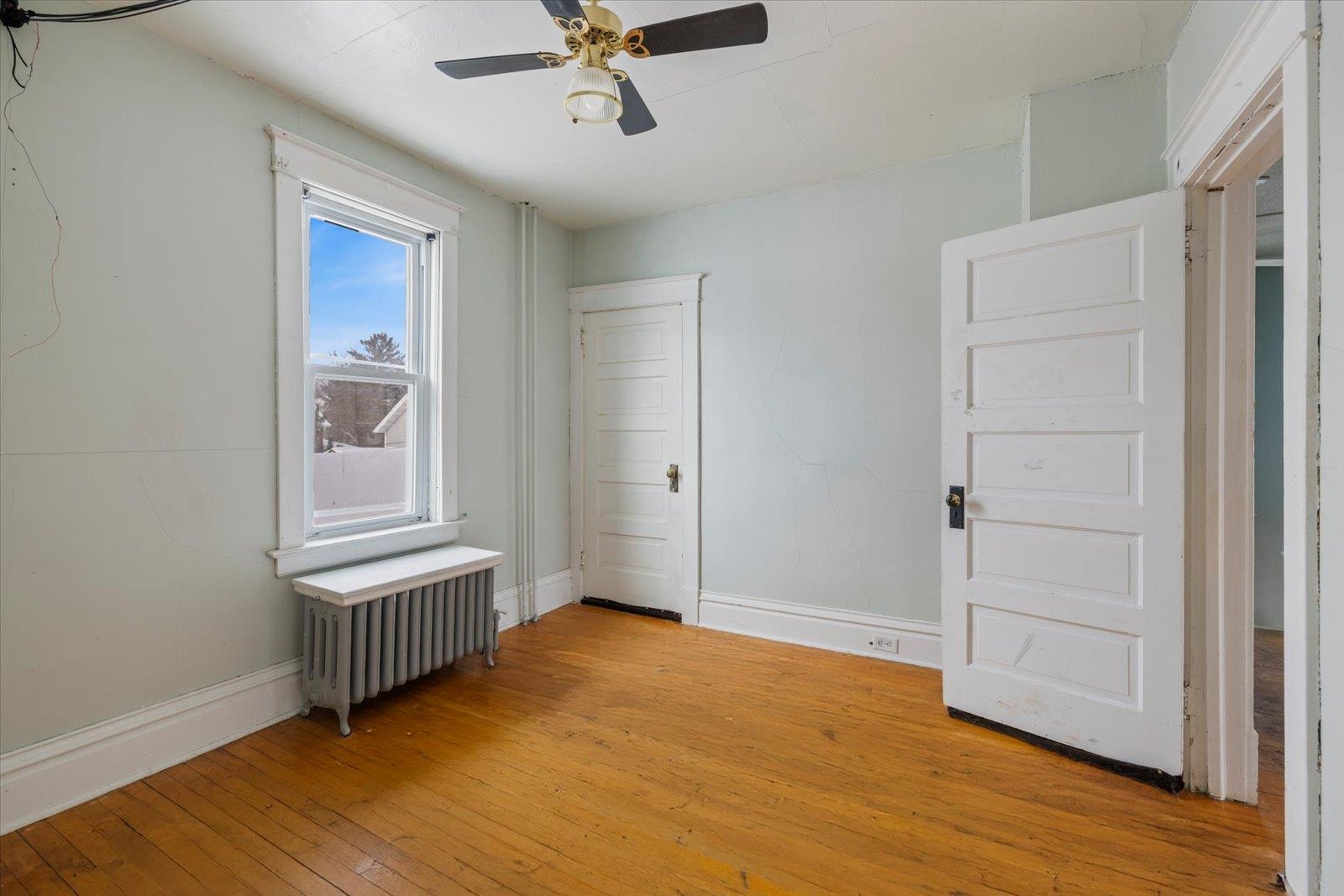 217 3rd Avenue Northwest Chisholm, MN 55719 - Photo 16 of 47 Unfurnished bedroom featuring radiator heating unit, light wood-type flooring, and a ceiling fan