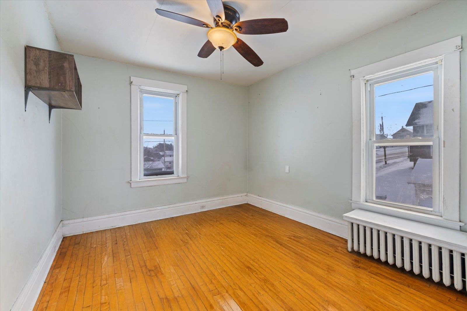 217 3rd Avenue Northwest Chisholm, MN 55719 - Photo 17 of 47 Unfurnished room featuring radiator, light wood-style flooring, and ceiling fan
