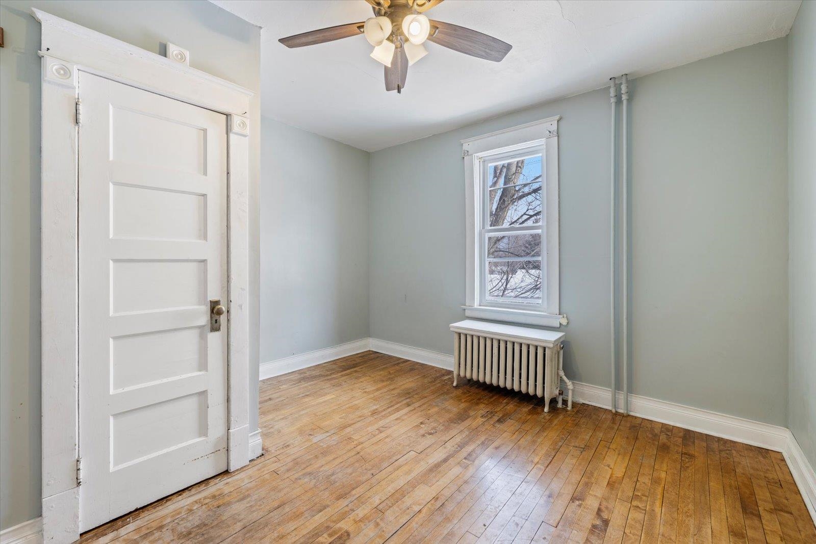 217 3rd Avenue Northwest Chisholm, MN 55719 - Photo 23 of 47 Spare room with radiator heating unit, light wood finished floors, and a ceiling fan