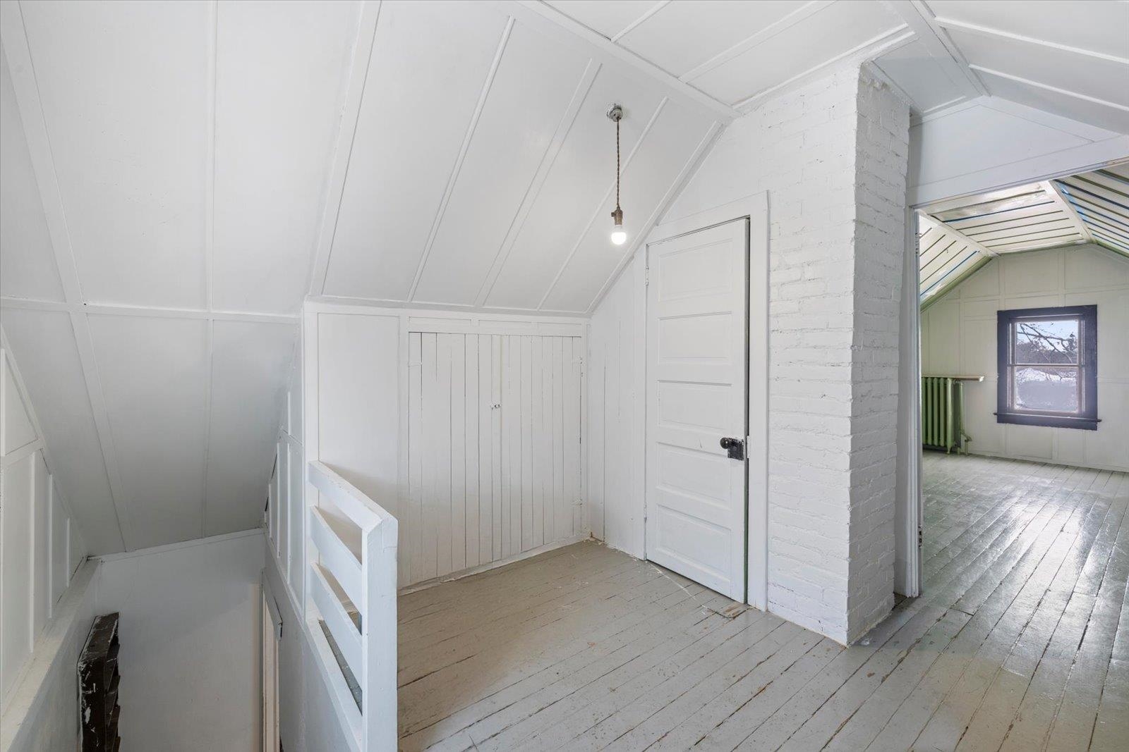 217 3rd Avenue Northwest Chisholm, MN 55719 - Photo 26 of 47 Additional living space featuring light wood-style flooring, lofted ceiling, radiator, and a decorative wall