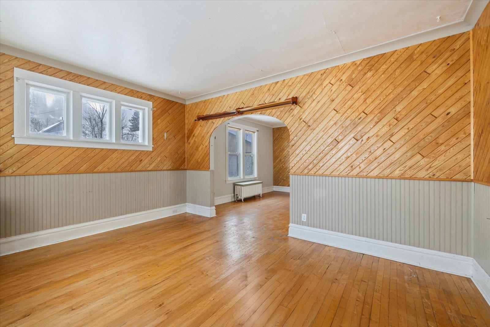 217 3rd Avenue Northwest Chisholm, MN 55719 - Photo 30 of 47 Spare room with wooden walls, radiator, light wood-style flooring, and healthy amount of natural light