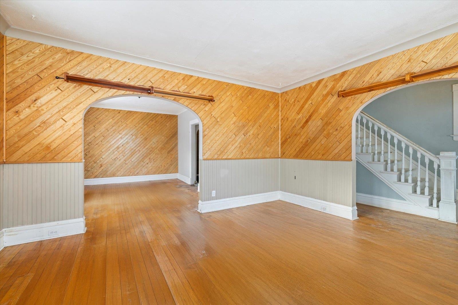 217 3rd Avenue Northwest Chisholm, MN 55719 - Photo 31 of 47 Unfurnished room featuring arched walkways, wood walls, stairs, and light wood-style flooring