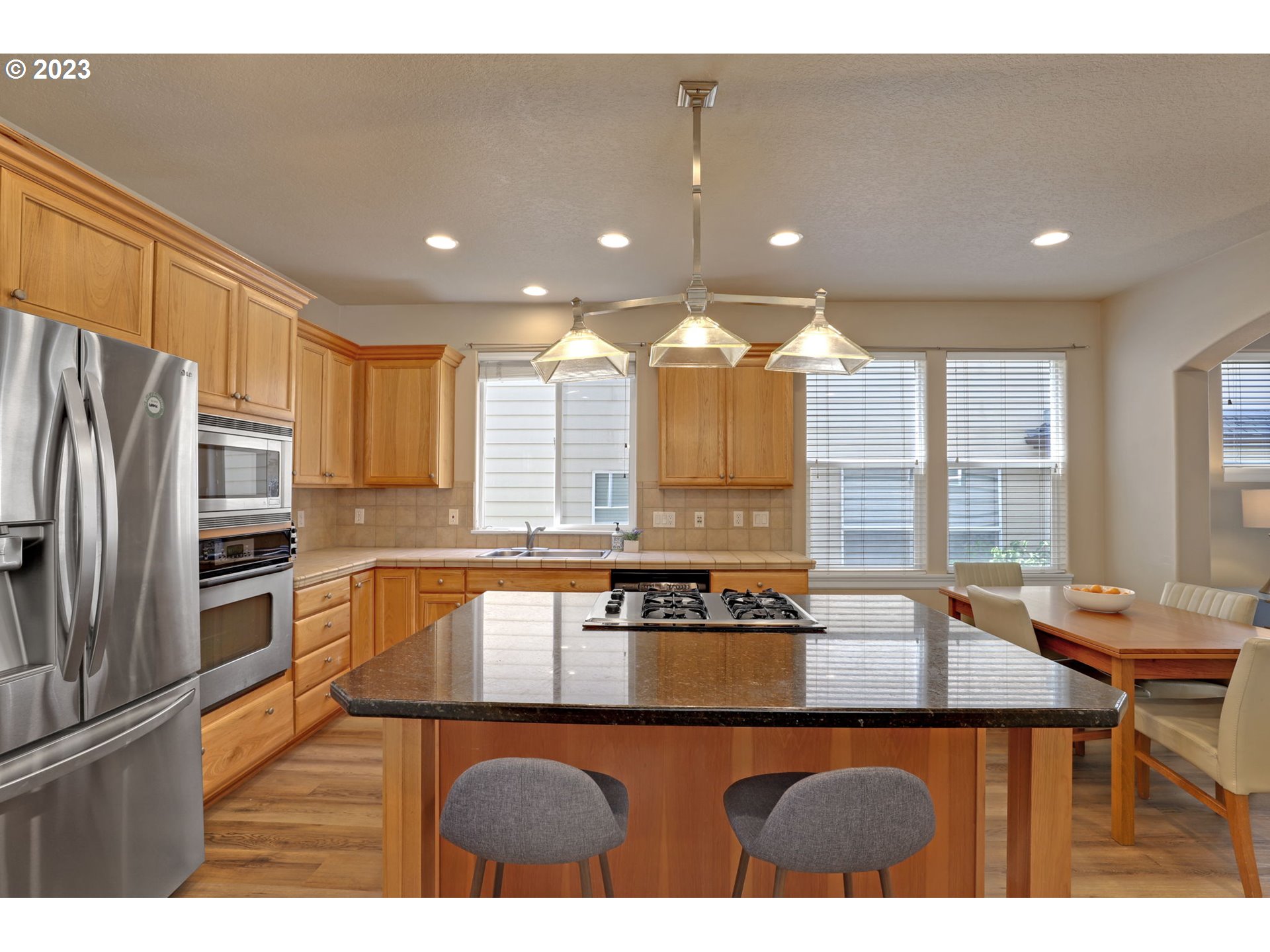 12799 Northwest Forest Spring Lane Portland, OR 97229 - Photo 10 of 30 a kitchen with stainless steel appliances granite countertop a sink a stove a refrigerator cabinets and living room view