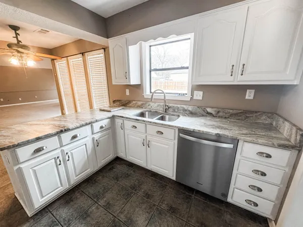 a kitchen with granite countertop white cabinets white appliances and a sink