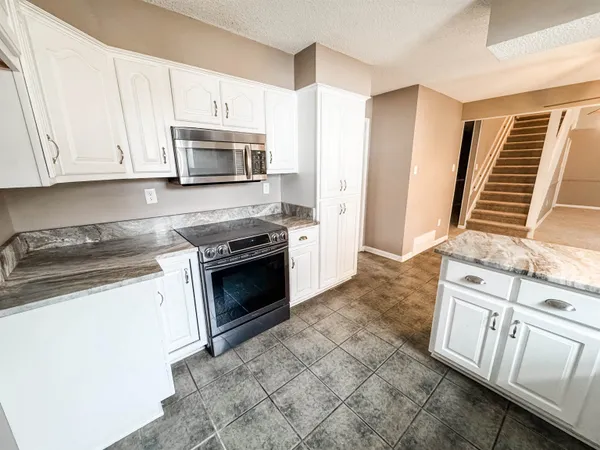 a kitchen with granite countertop a stove top oven a sink and dishwasher