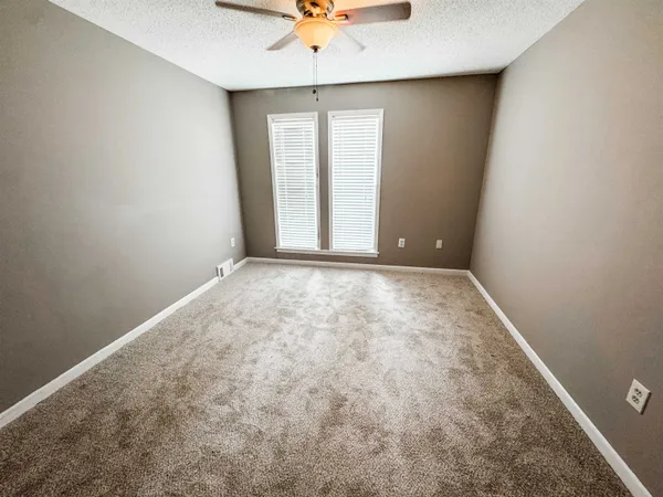 an empty room with a window and a ceiling fan