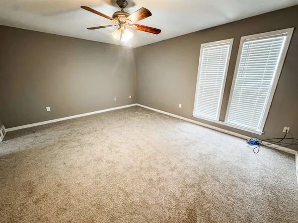 an empty room with windows and fan