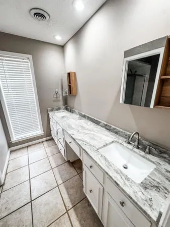 a bathroom with a granite countertop sink and a mirror
