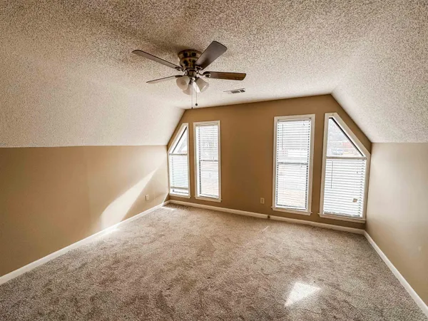 an empty room with windows and fan