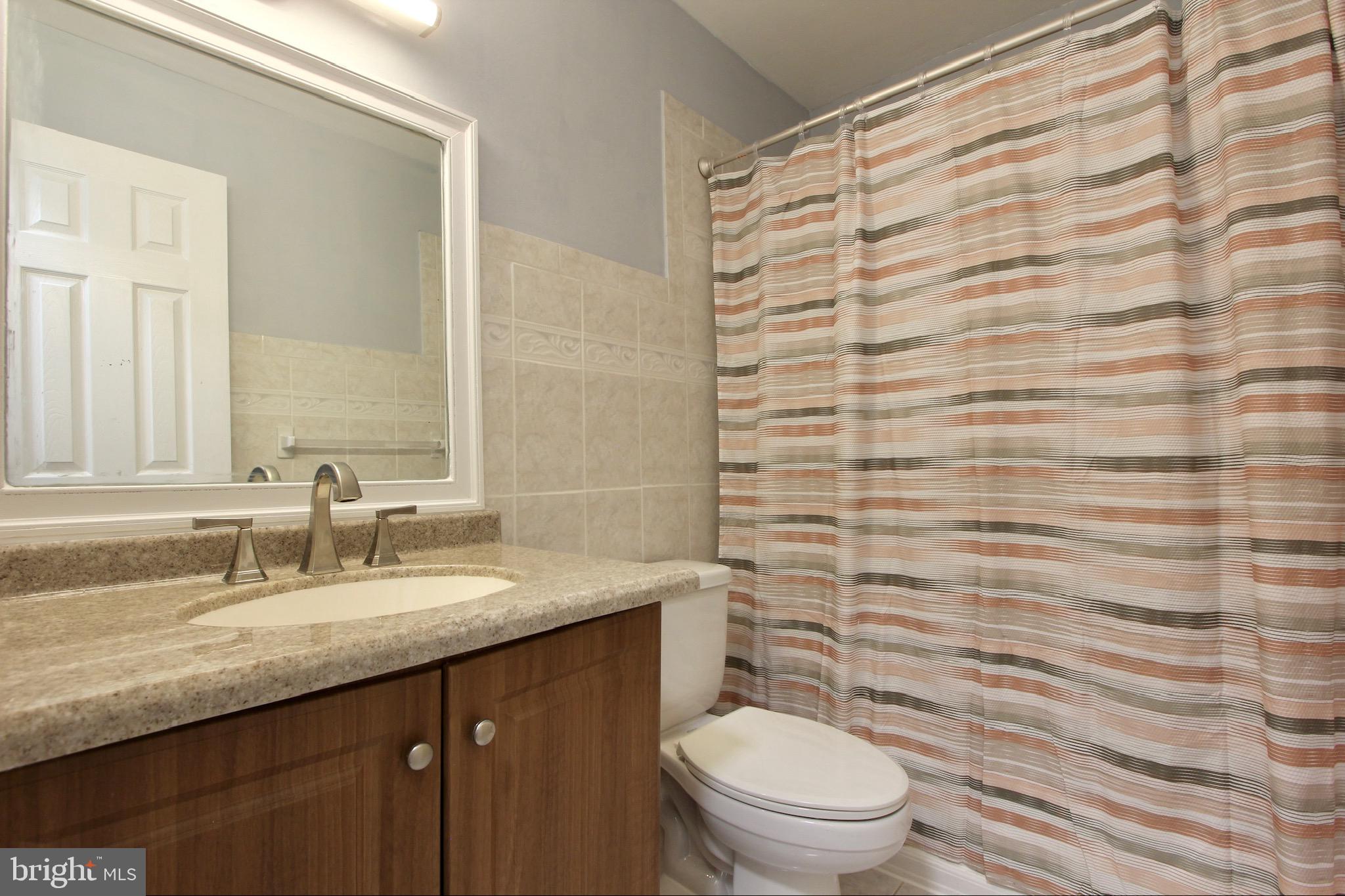 14426 Parkvale Road, Unit 5 Rockville, MD 20853 - Photo 21 of 26 a bathroom with a granite countertop sink toilet and shower