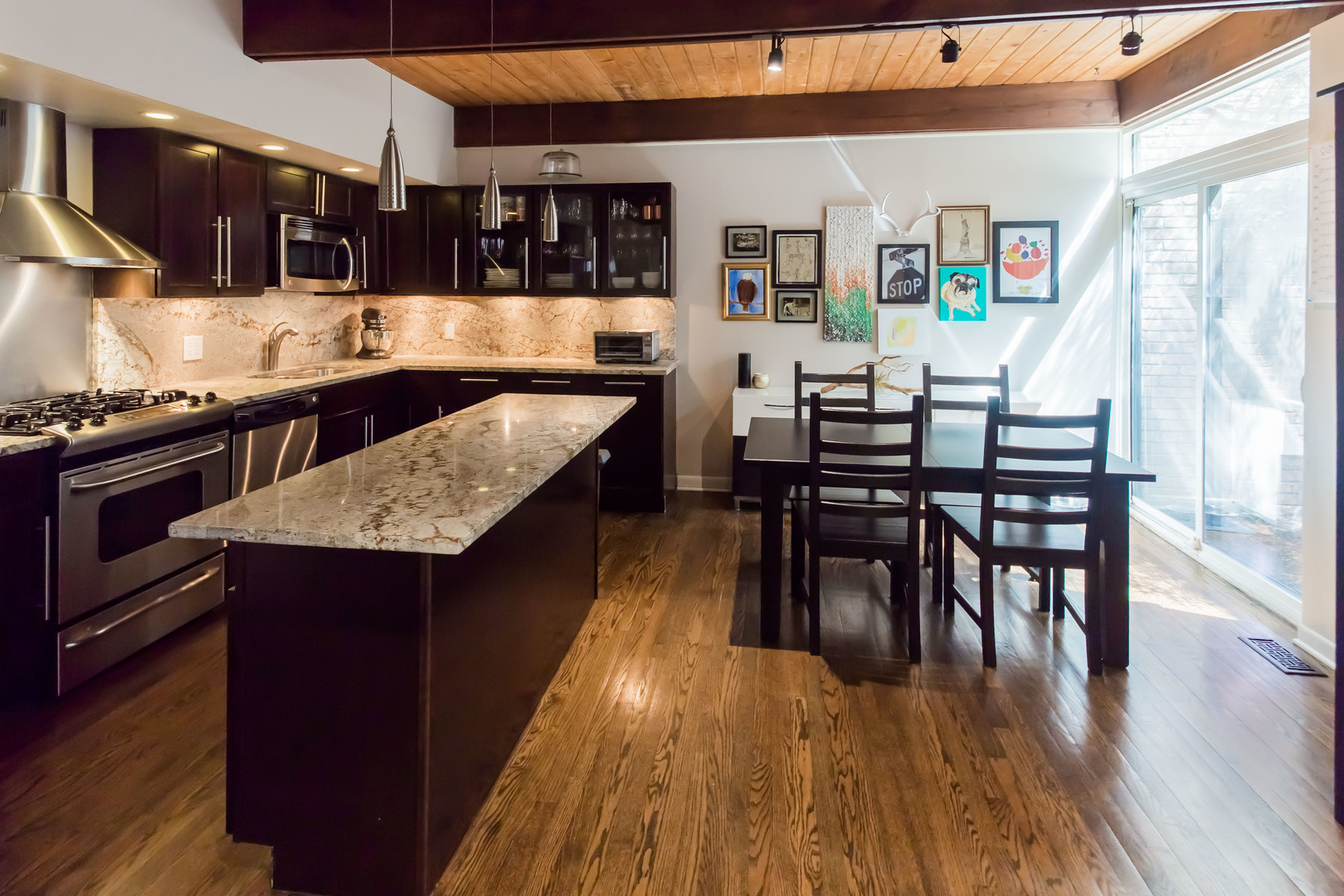 3012 North Waterloo Court, Unit 5 Chicago, IL 60657 - Photo 5 of 19 a kitchen with stainless steel appliances granite countertop a stove top oven a sink a dining table and chairs with wooden floor