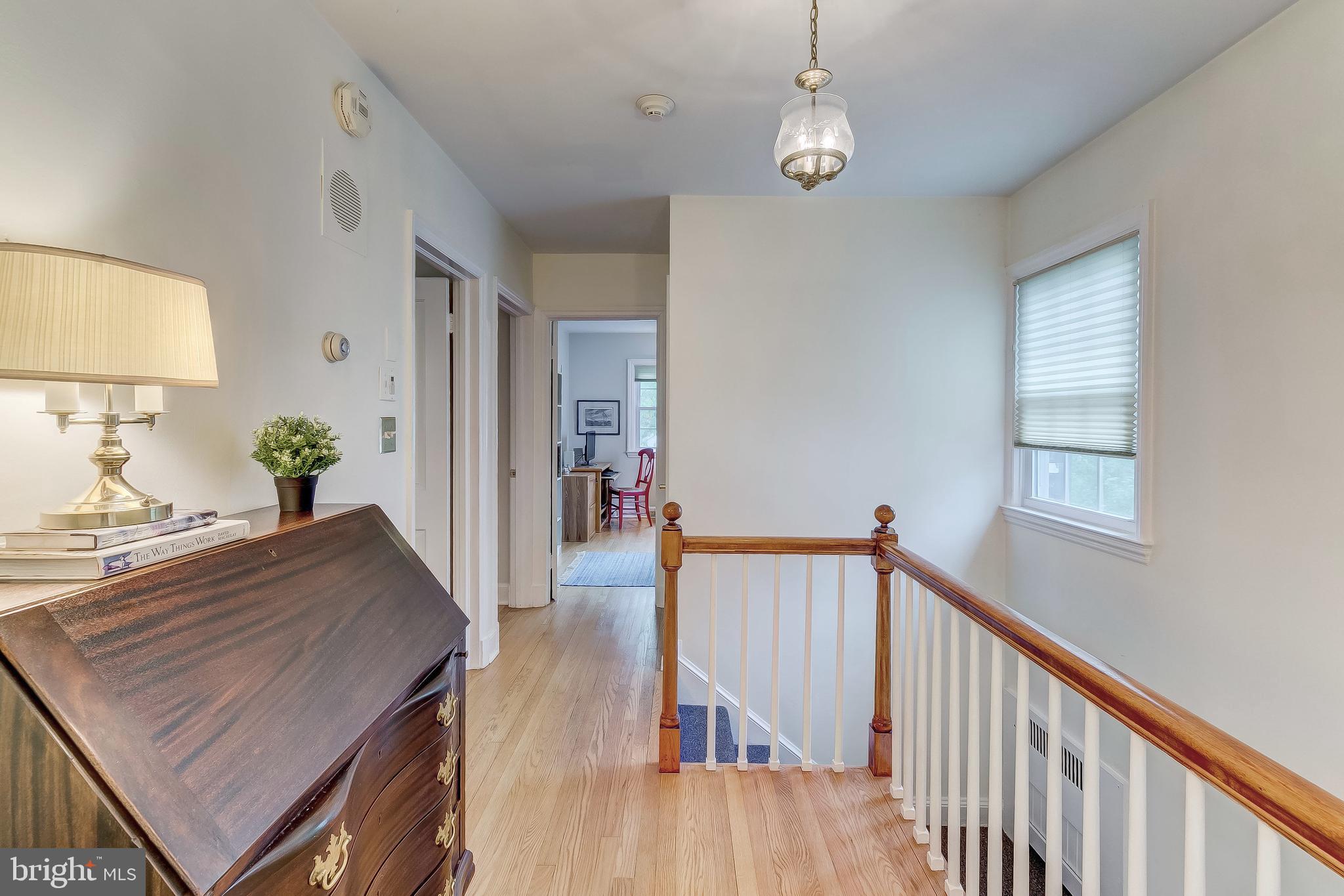 5704 Kenmore Road Baltimore, MD 21210 - Photo 14 of 30 a hallway with wooden floor windows and a chandelier