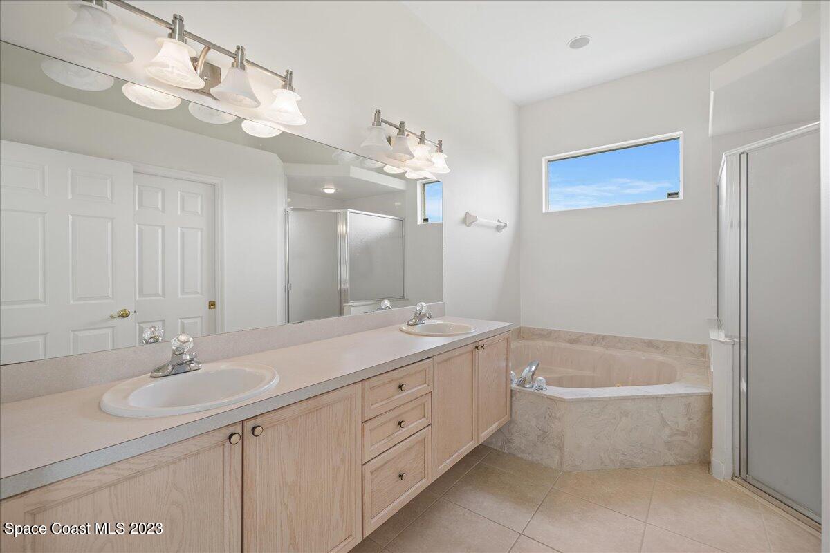 853 Villa Drive Melbourne, FL 32940 - Photo 19 of 28 a bathroom with a double vanity sink a mirror and a bathtub