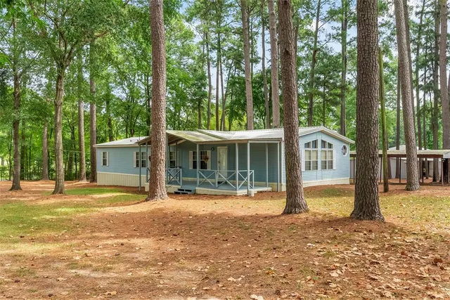 a view of a house with backyard and trees