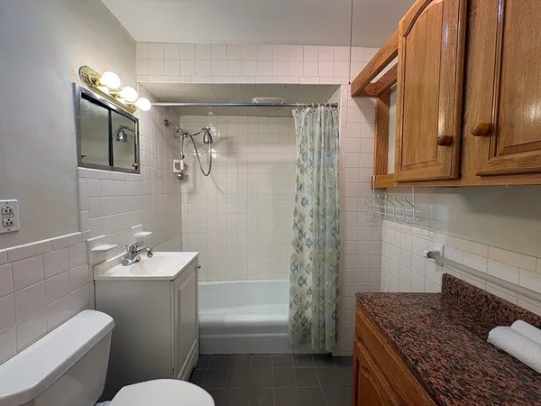 a bathroom with a granite countertop sink a toilet a mirror and shower