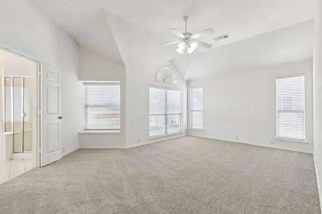 an empty room with chandelier fan and windows