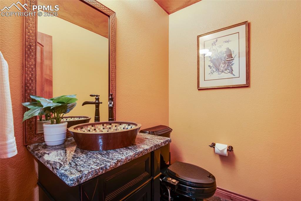 16075 Winding Trail Road Colorado Springs, CO 80908 - Photo 19 of 42 a bathroom with a granite countertop toilet and a sink