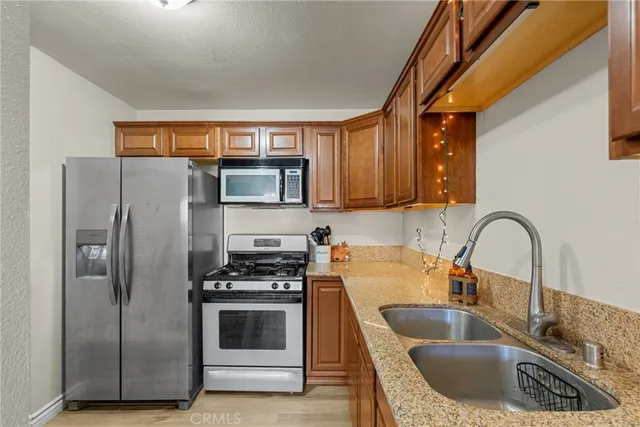 a kitchen with granite countertop a sink stainless steel appliances and cabinets
