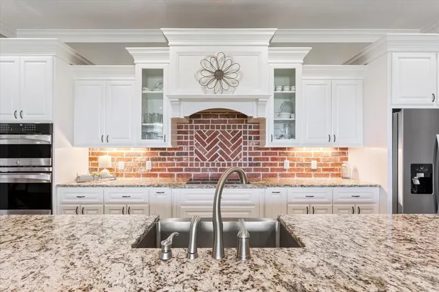 a kitchen with granite countertop a stove a sink and a refrigerator
