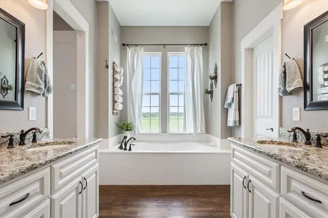 a bathroom with a granite countertop sink mirror and a bathtub