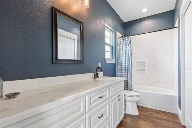 a bathroom with a granite countertop sink a toilet and shower