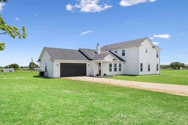 a house that is sitting in the grass with large trees