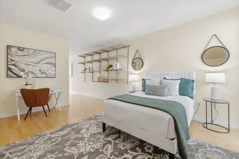 a bedroom with a bed and chair with a wooden floor
