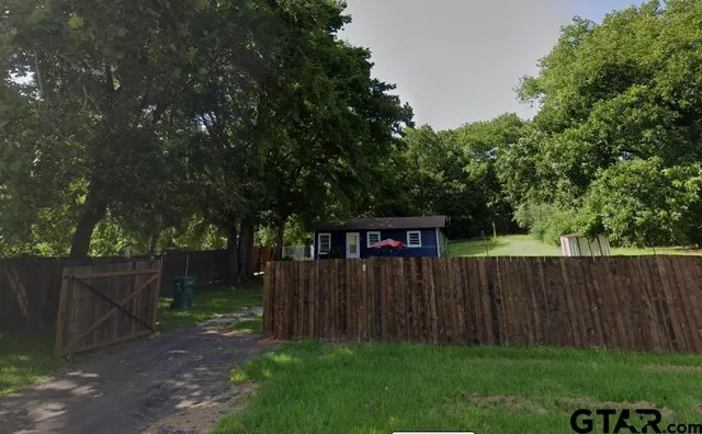 a view of a backyard with wooden fence and a large tree