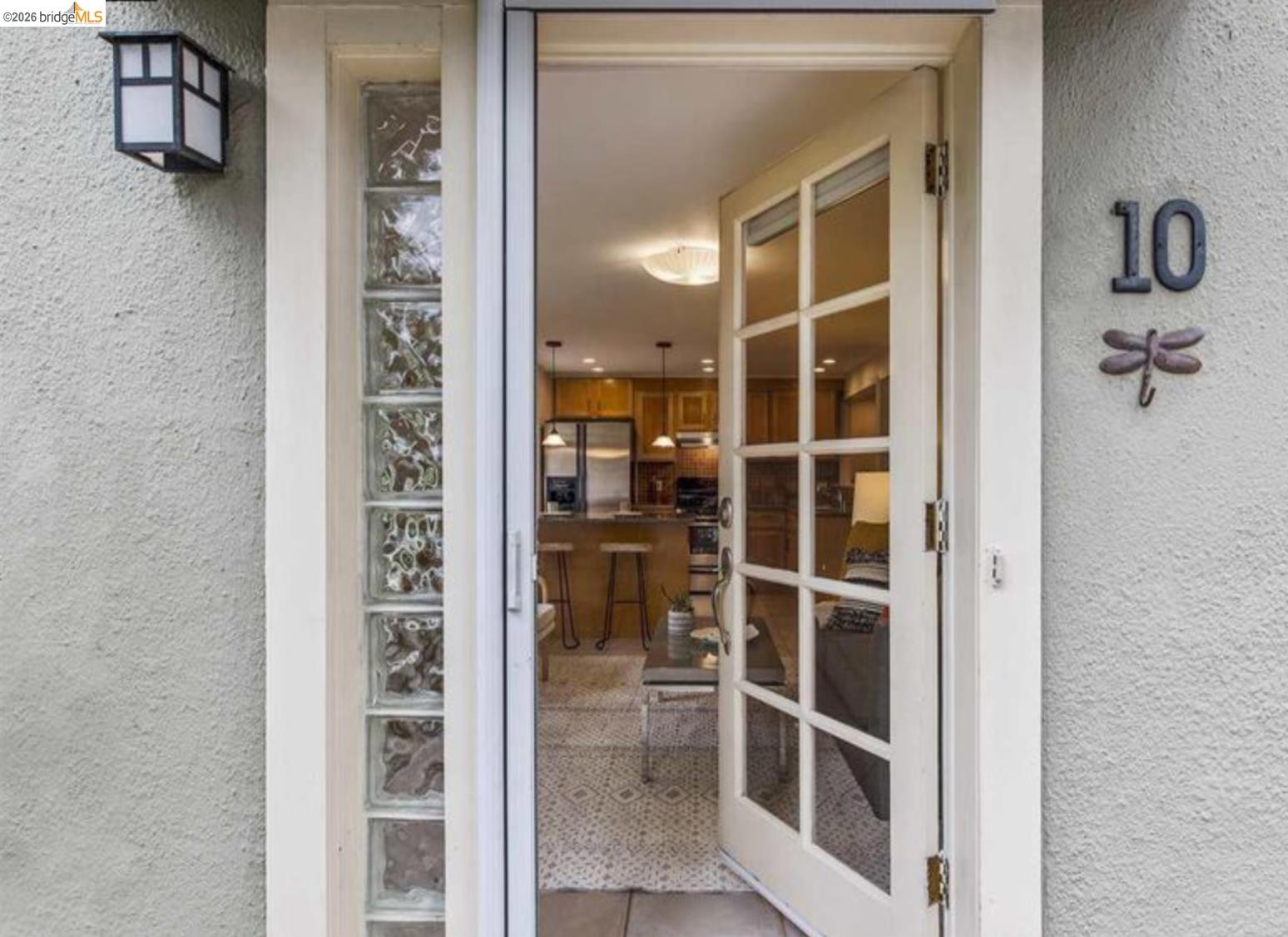 2725 Prince Street, Unit 10 Berkeley, CA 94705 - Photo 1 of 2 Entryway featuring a glass-paned door, textured exterior wall, and vertical glass block sidelight
