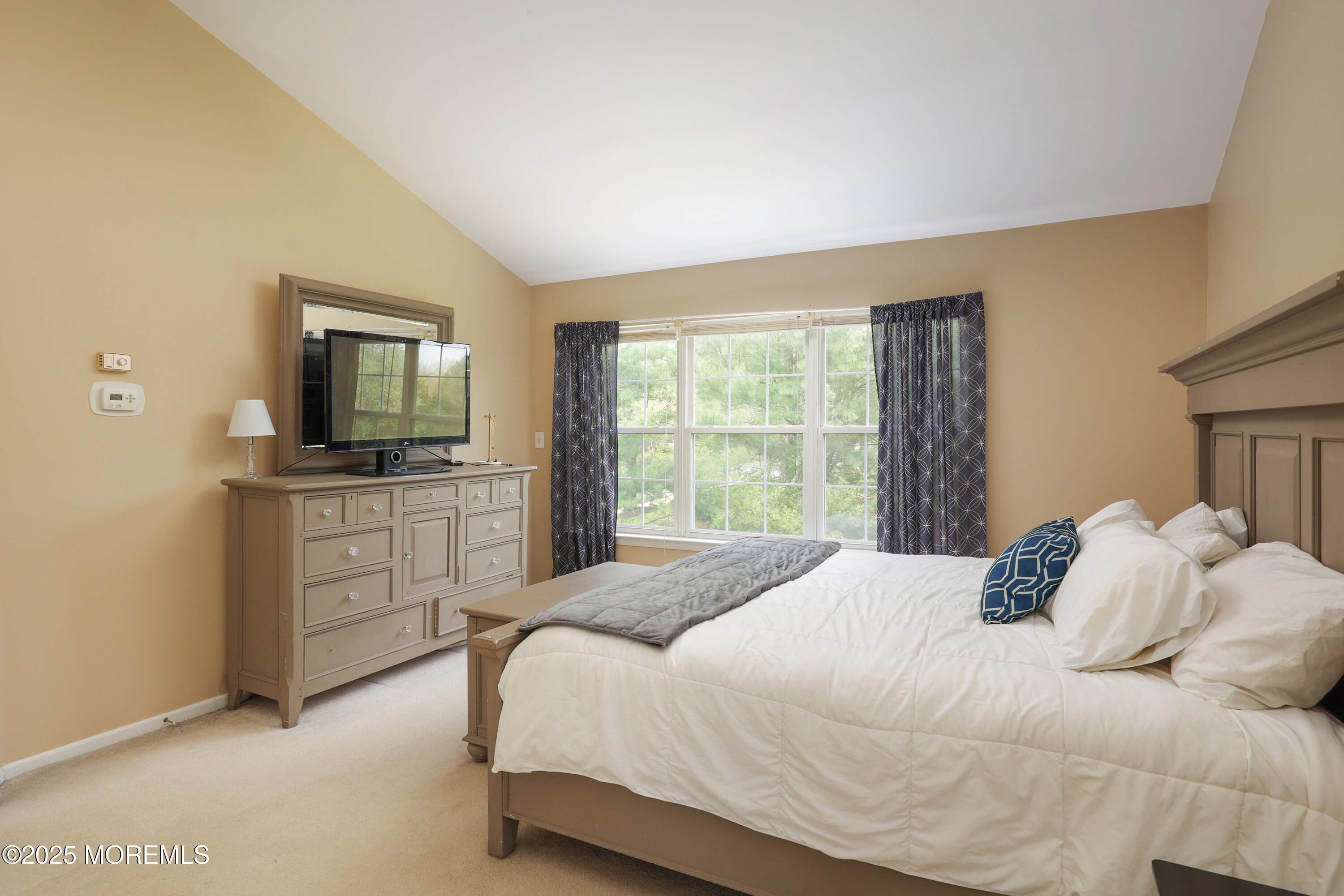1 Exeter Pass Colts Neck, NJ 07722 - Photo 25 of 42 a bedroom with a large bed and a flat tv screen on dresser