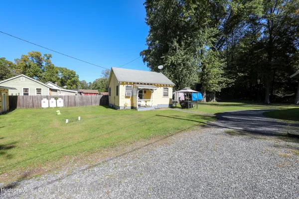 a view of house with a big yard and large trees