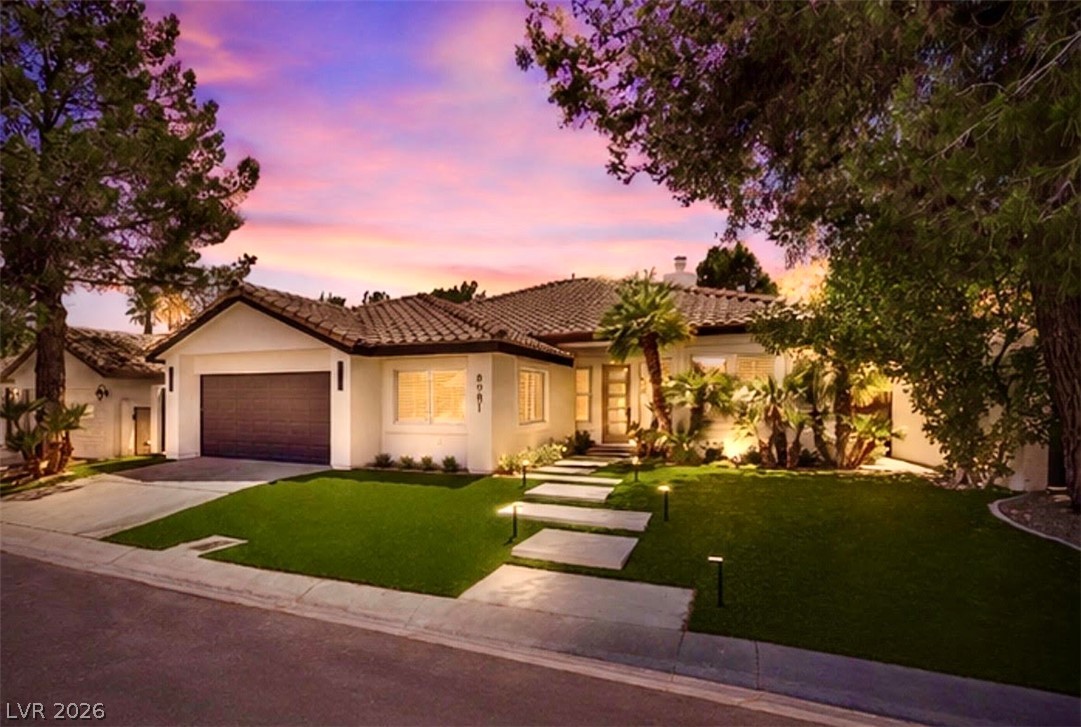 Elegant single-story home featuring a meticulously landscaped front yard with modern pathway lighting.