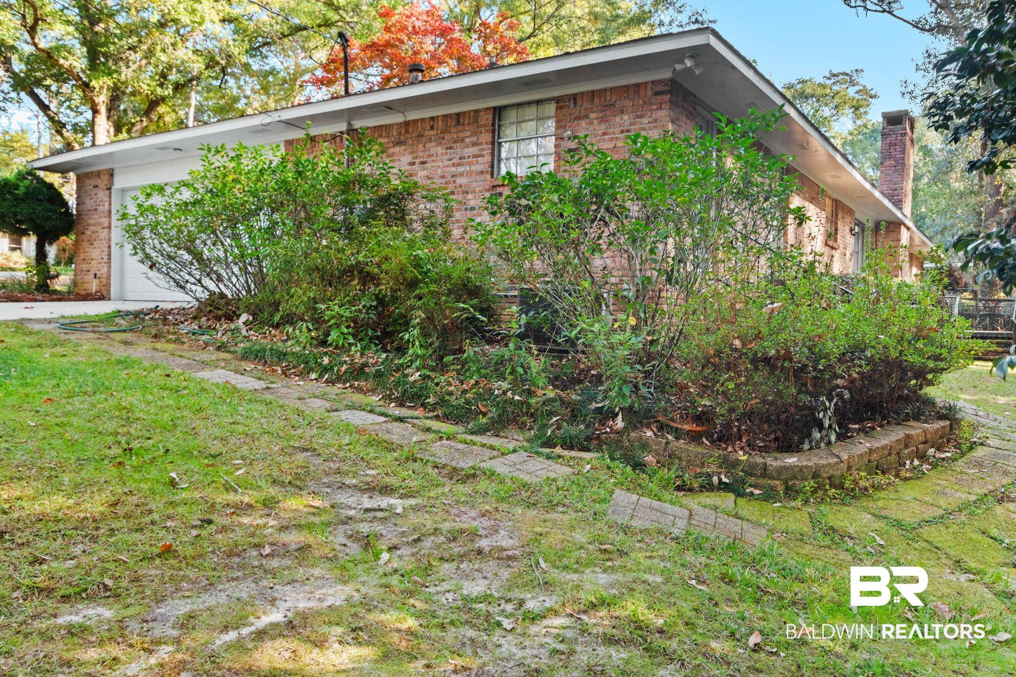752 Evergreen Street Fairhope, AL 36532 - Photo 75 of 100 View of home's exterior with a chimney, brick siding, a lawn, and a garage
