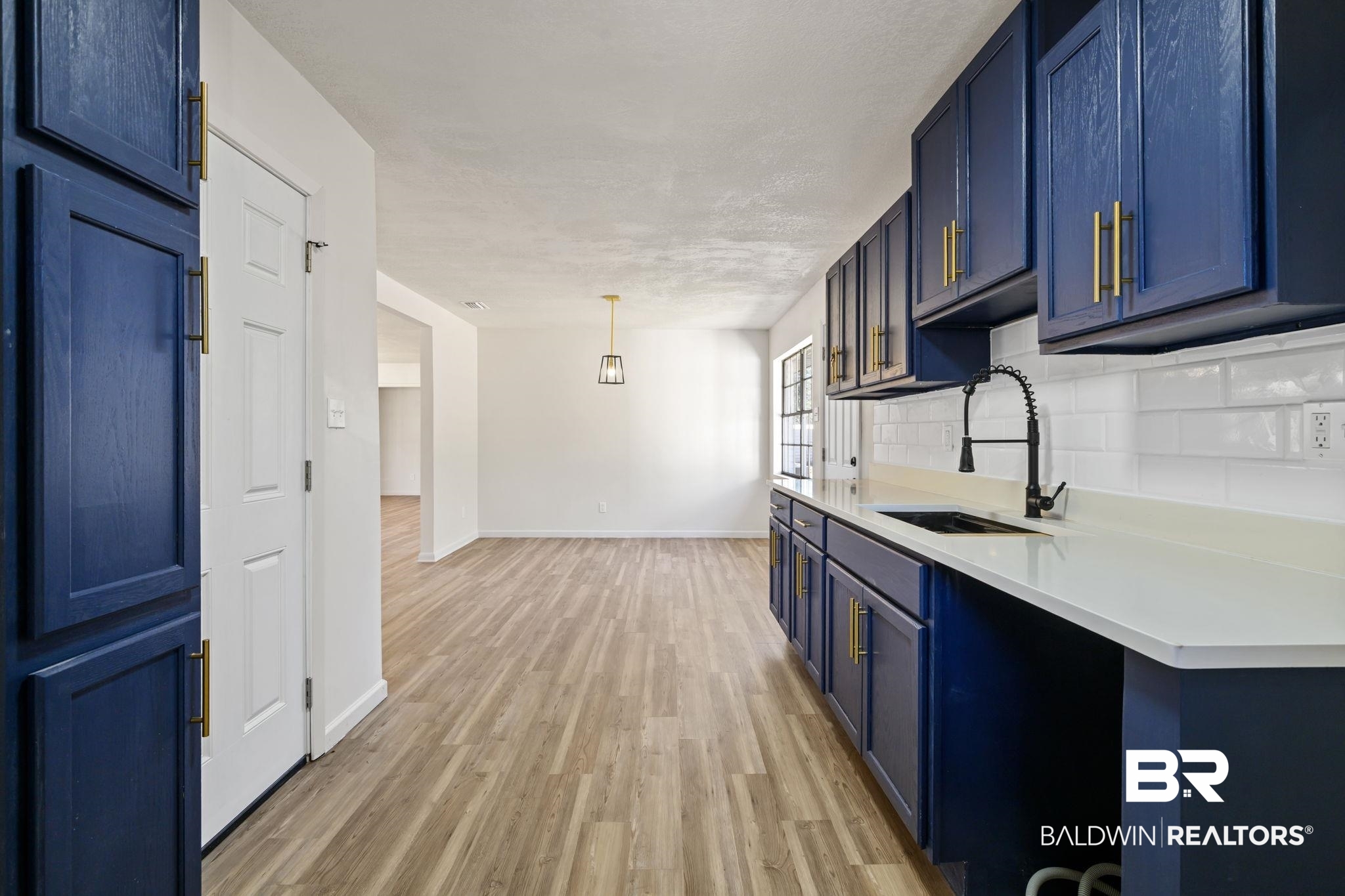 910 Moran Street Bay Minette, AL 36507 - Photo 6 of 20 Kitchen with blue cabinets, light wood-type flooring, decorative light fixtures, and decorative backsplash
