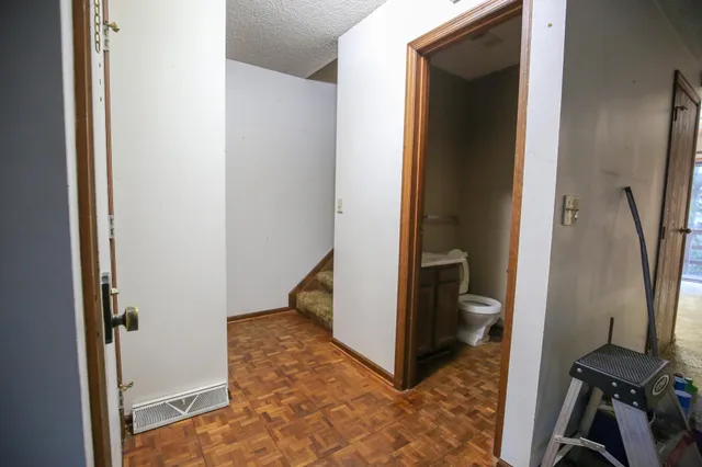 a view of a hallway with wooden floor and a bathroom