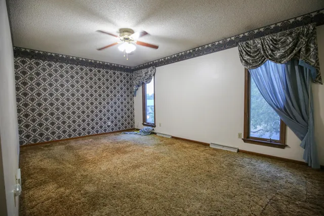 an empty room with window and ceiling fan