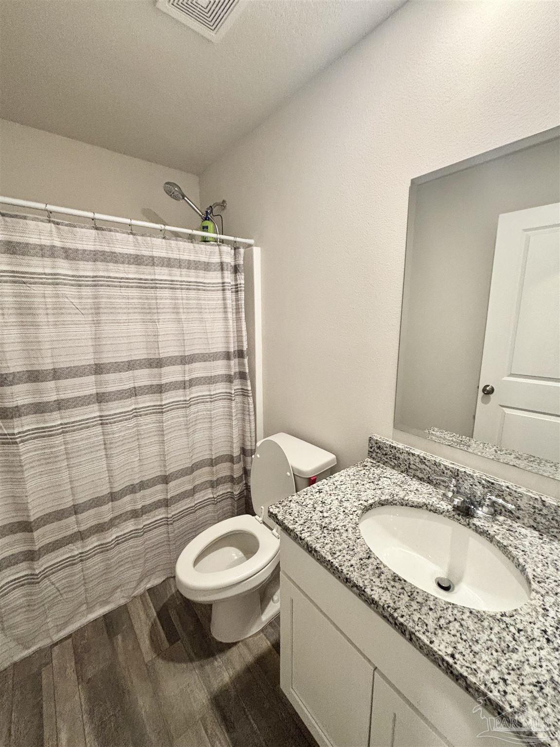 2164 Pineview Church Road Jay, FL 32565 - Photo 18 of 24 a bathroom with a granite countertop sink toilet a mirror and shower curtain