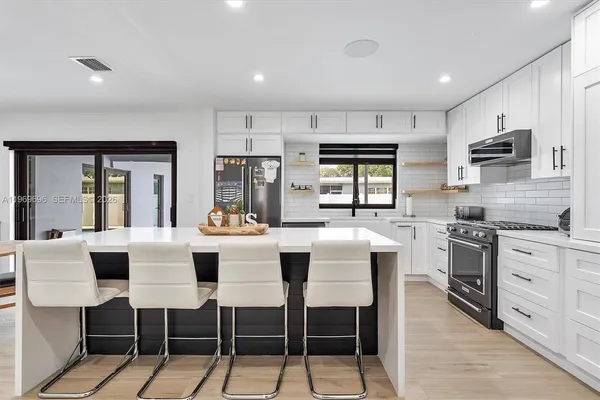 a dining hall with stainless steel appliances kitchen island granite countertop a dining table and chairs