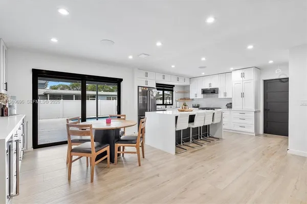 a living room with stainless steel appliances kitchen island granite countertop furniture and a wooden floor
