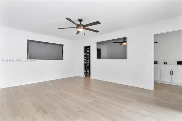 a view of an empty room with wooden floor and a flat screen tv