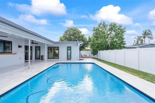 a view of a backyard with a swimming pool and sitting area