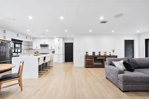 a living room with stainless steel appliances kitchen island furniture and a table