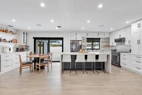 a large white kitchen with lots of counter space dining table and chairs