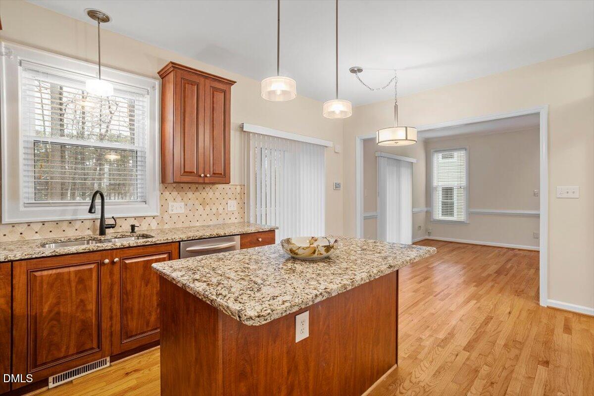 2628 Crofton Springs Drive Raleigh, NC 27615 - Photo 14 of 33 a kitchen with granite countertop kitchen island wooden floor center island and stainless steel appliances