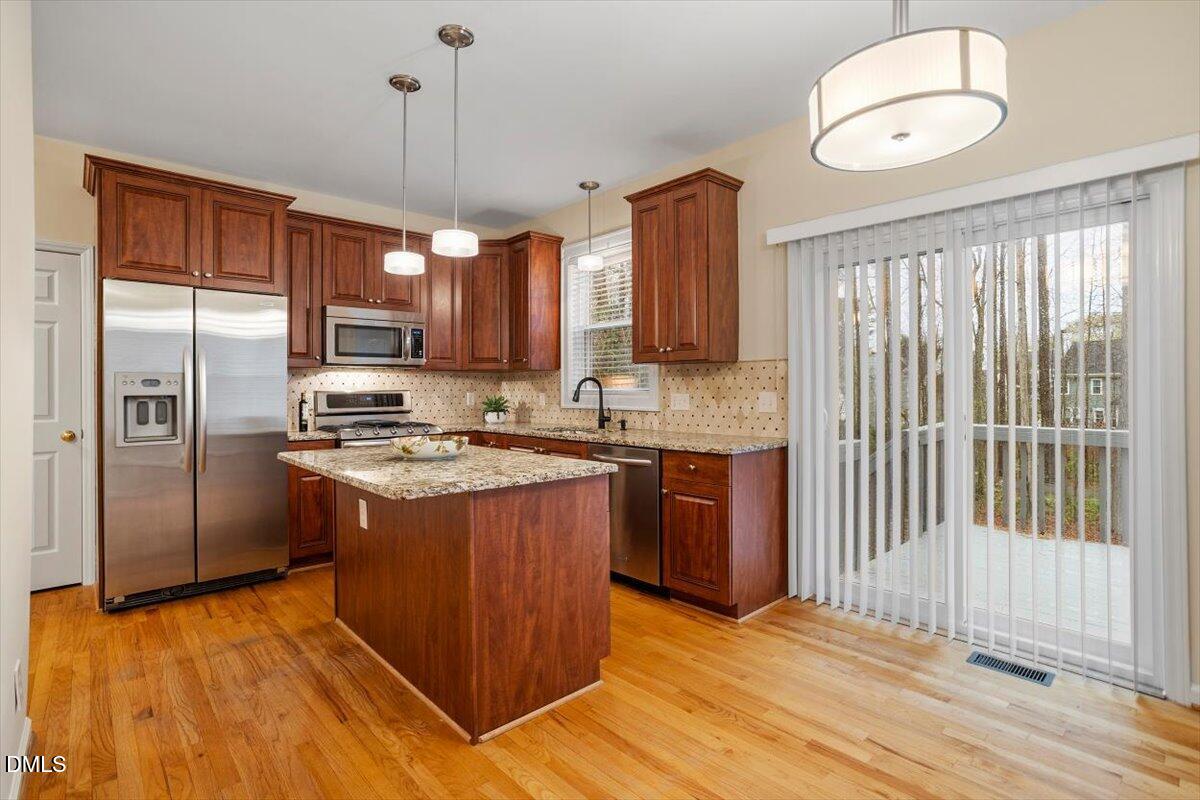 2628 Crofton Springs Drive Raleigh, NC 27615 - Photo 16 of 33 a kitchen with stainless steel appliances granite countertop a refrigerator a sink dishwasher a stove and a dining table with wooden floor