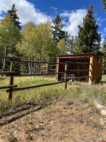 a backyard of a house with wooden fence and large trees