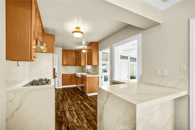 a kitchen with a stove a sink dishwasher and a refrigerator with wooden floor